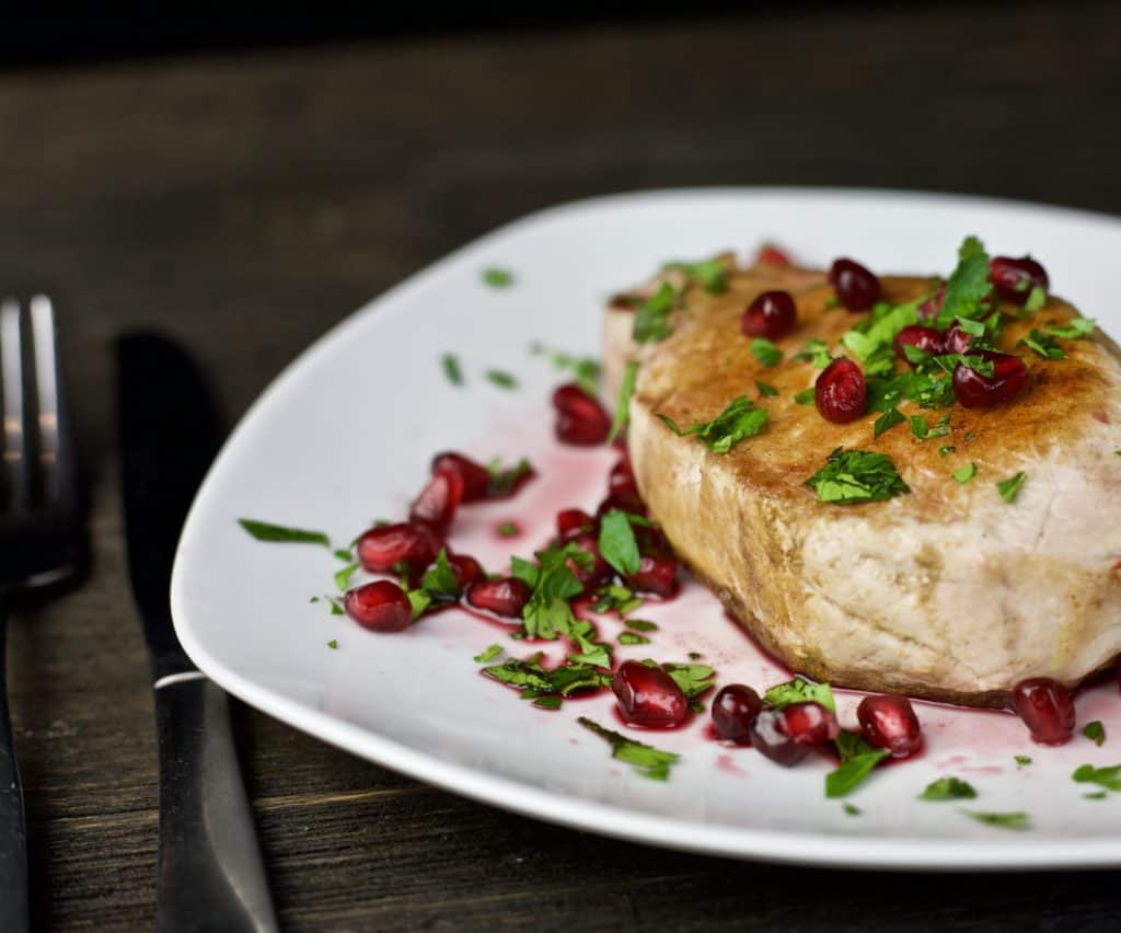 dinner plate with grilled pork chop and pomegranate