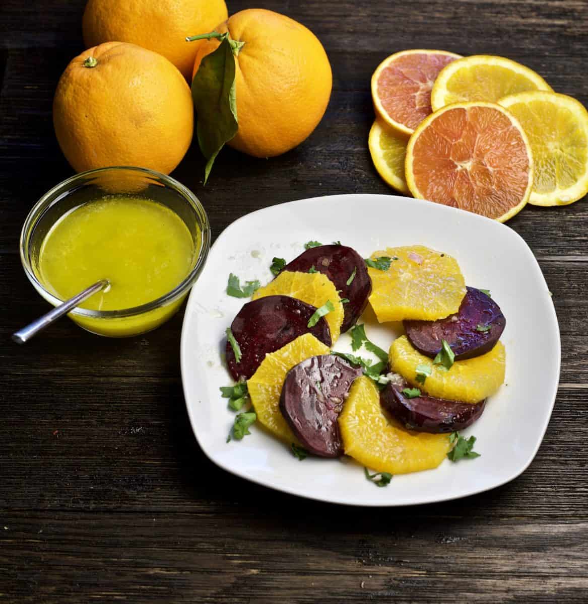 beet and orange salad with citrus vinaigrette on side and sliced oranges in top corner