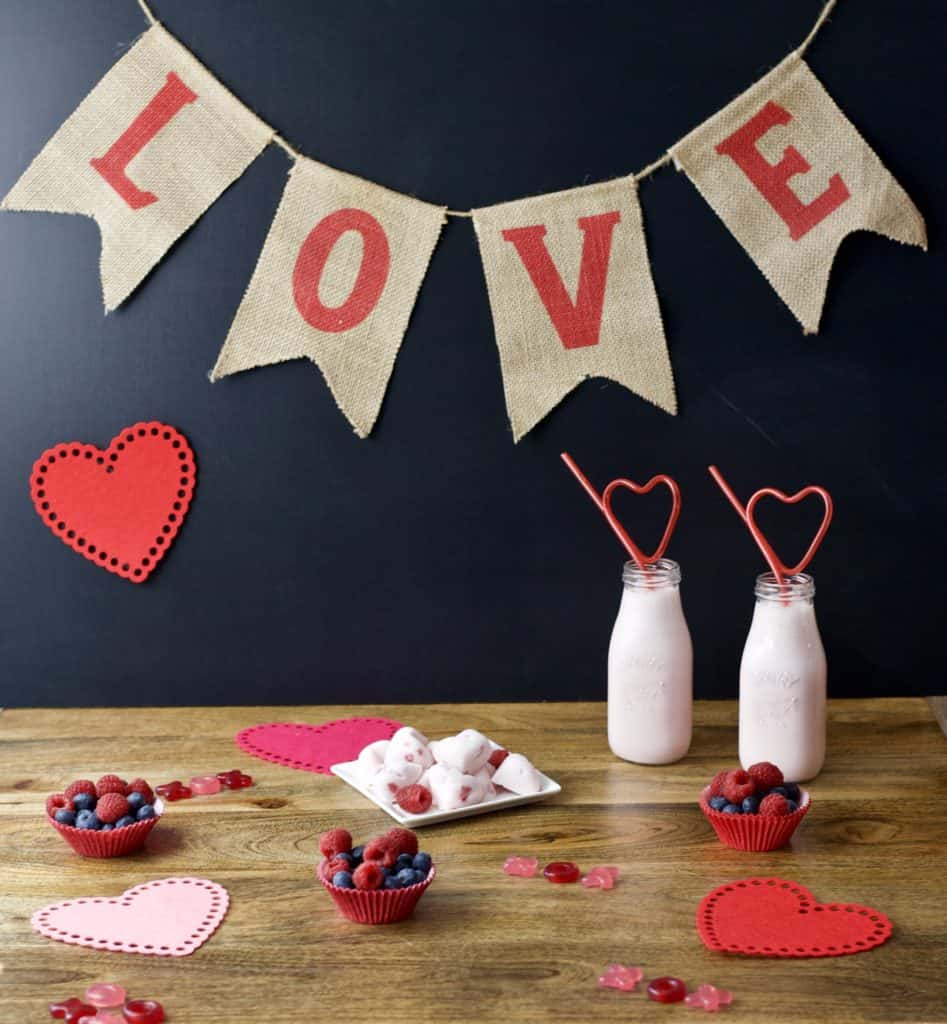 LOVE banner with strawberry smoothie, berry cups and yogurt hearts on holiday decorated table