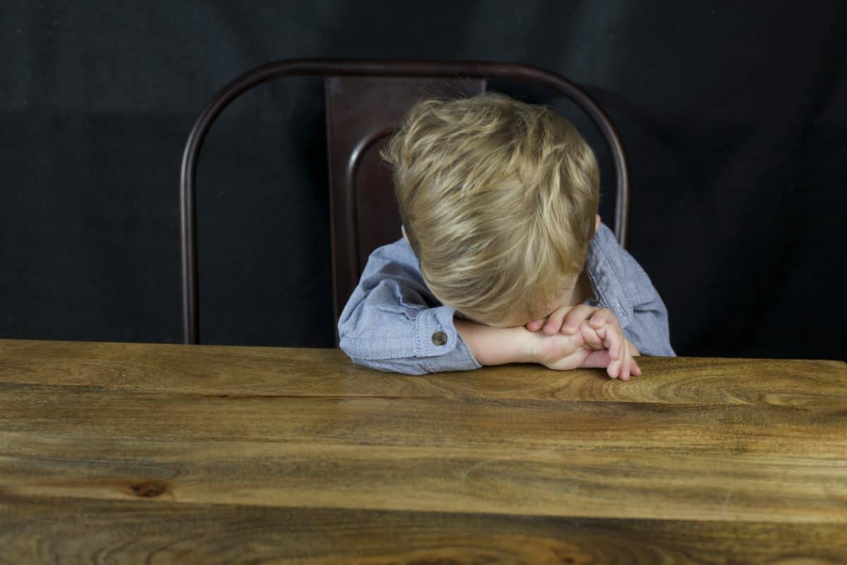 toddler boy with head down at dinner table