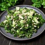 quinoa and fresh herb salad on a plate with fresh herbs and lime in the background