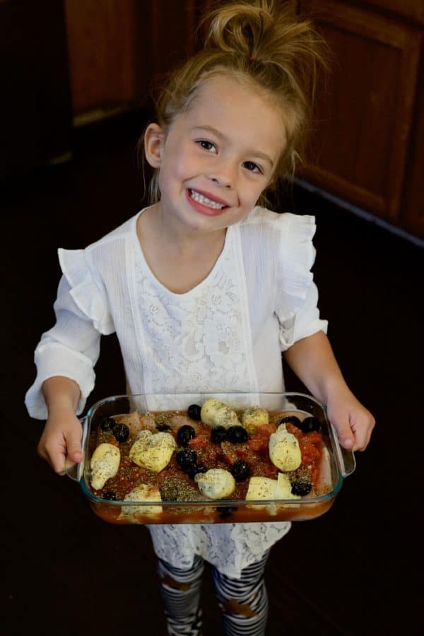 girl holding up pan of italian chicken bake