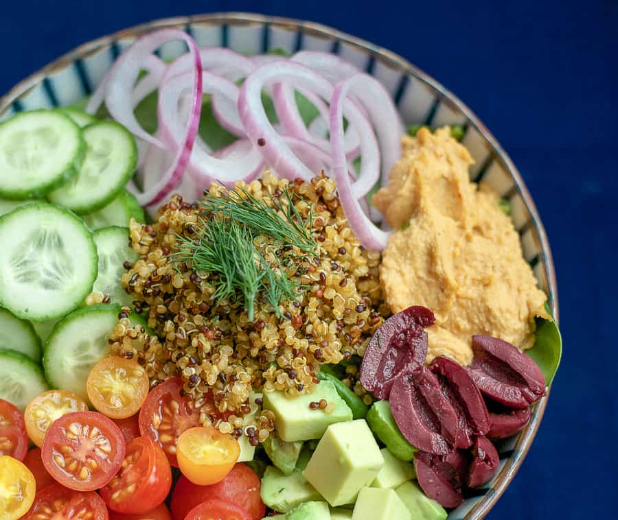 mediterranean plan protein power bowl - quinoa, hummus, olives, cucumber and tomato in a bowl