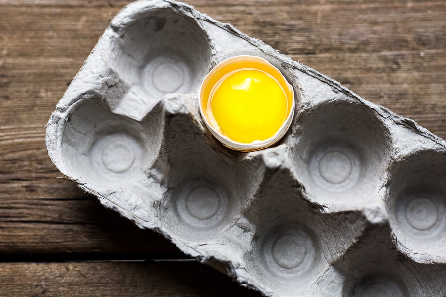 cracked egg in an empty cardboard carton