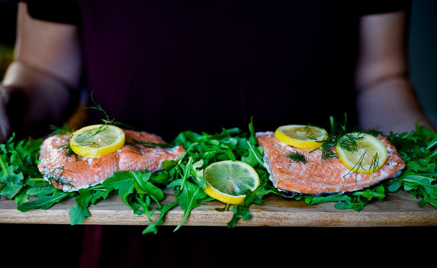 salmon with lemon being carried on wood tray for health benefits of seafood