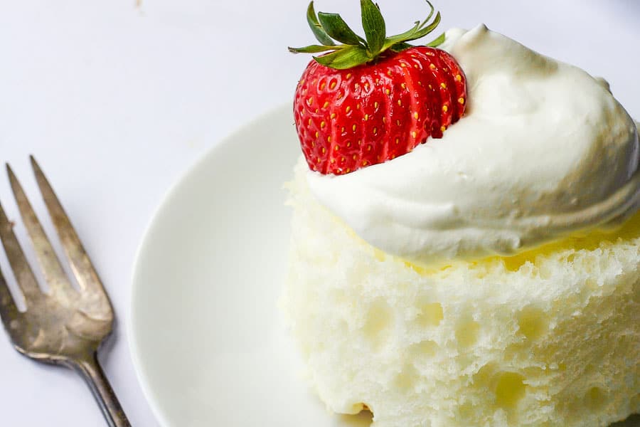 close up mini angel food cake topped with fresh strawberries and almond whipped cream