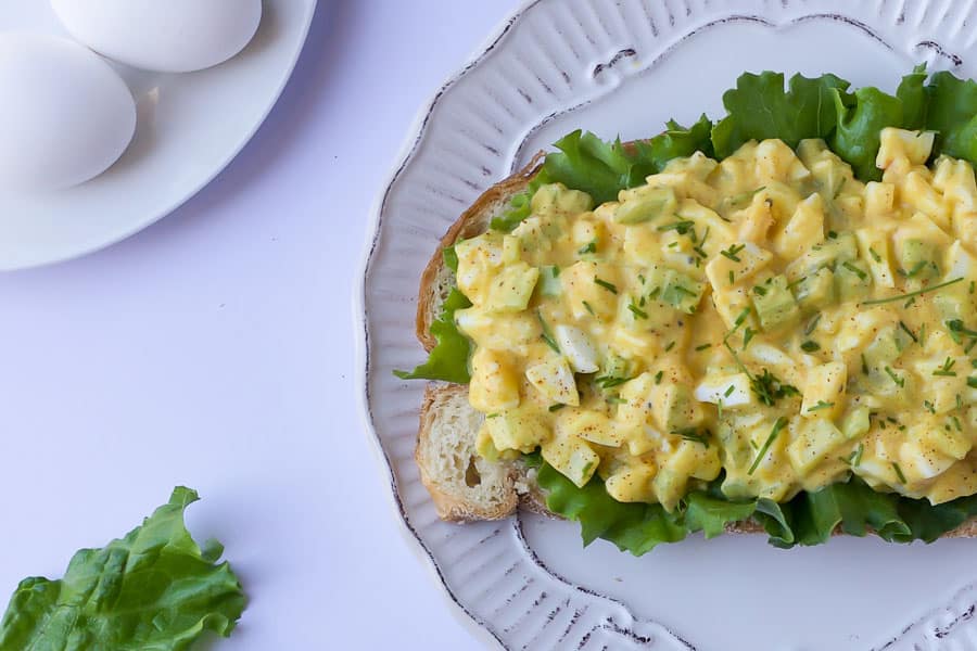 curry egg salad on toast with lettuce and hardboiled eggs in background