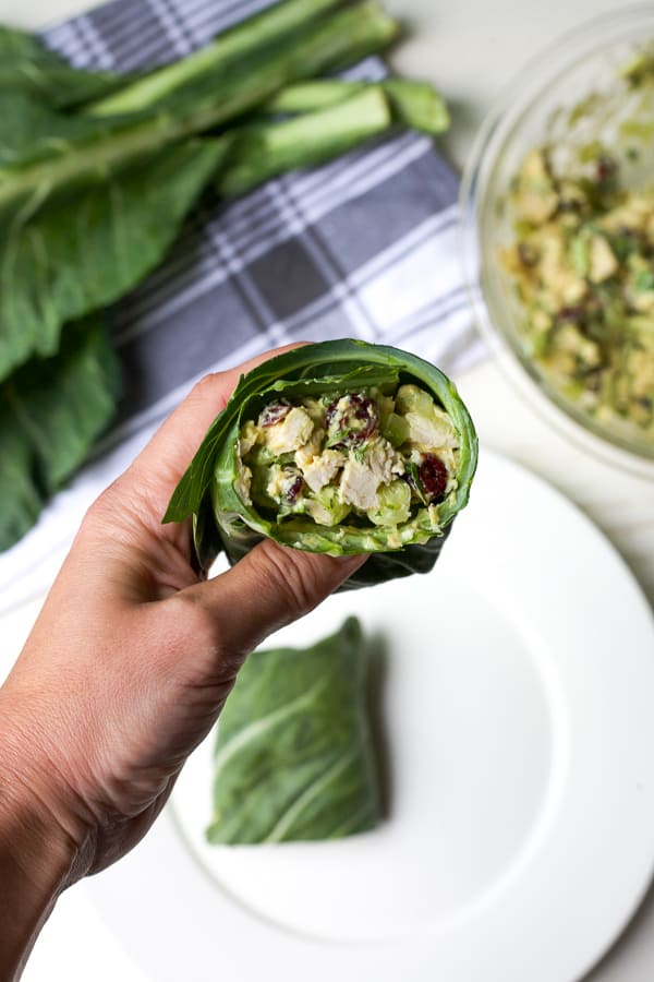 hand holding chicken salad collard green wrap