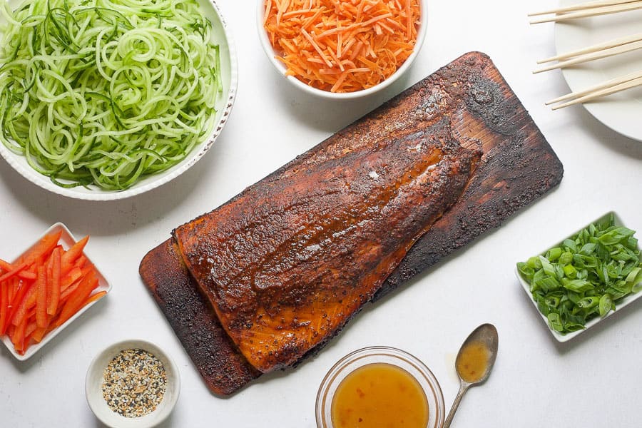 grilled cedar plank salmon with bowls of assorted vegetables