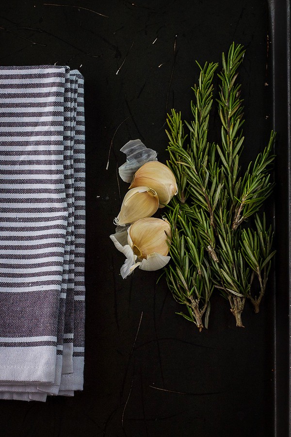 rosemary and garlic on a sheet pan with a towel