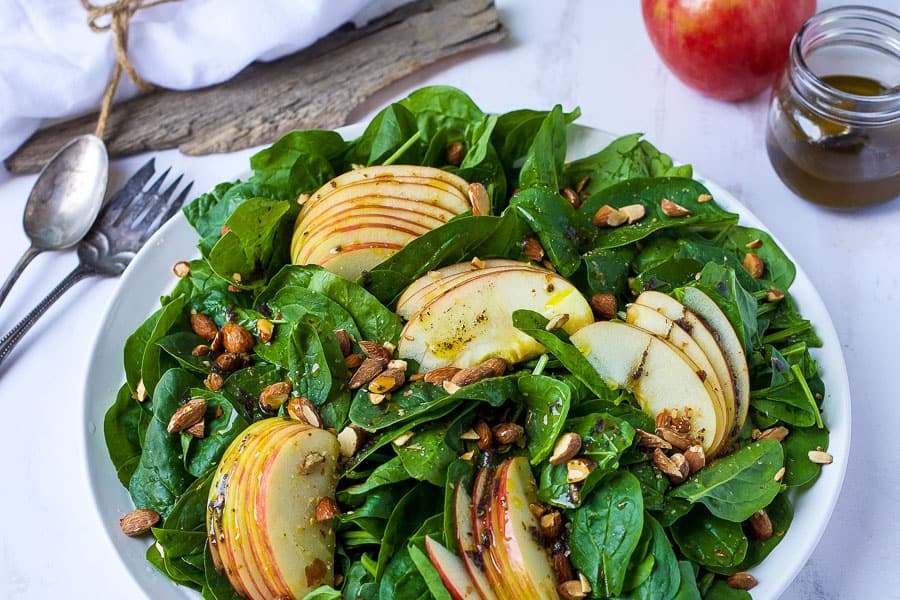 large bowl of almond apple spinach salad with sumac dressing