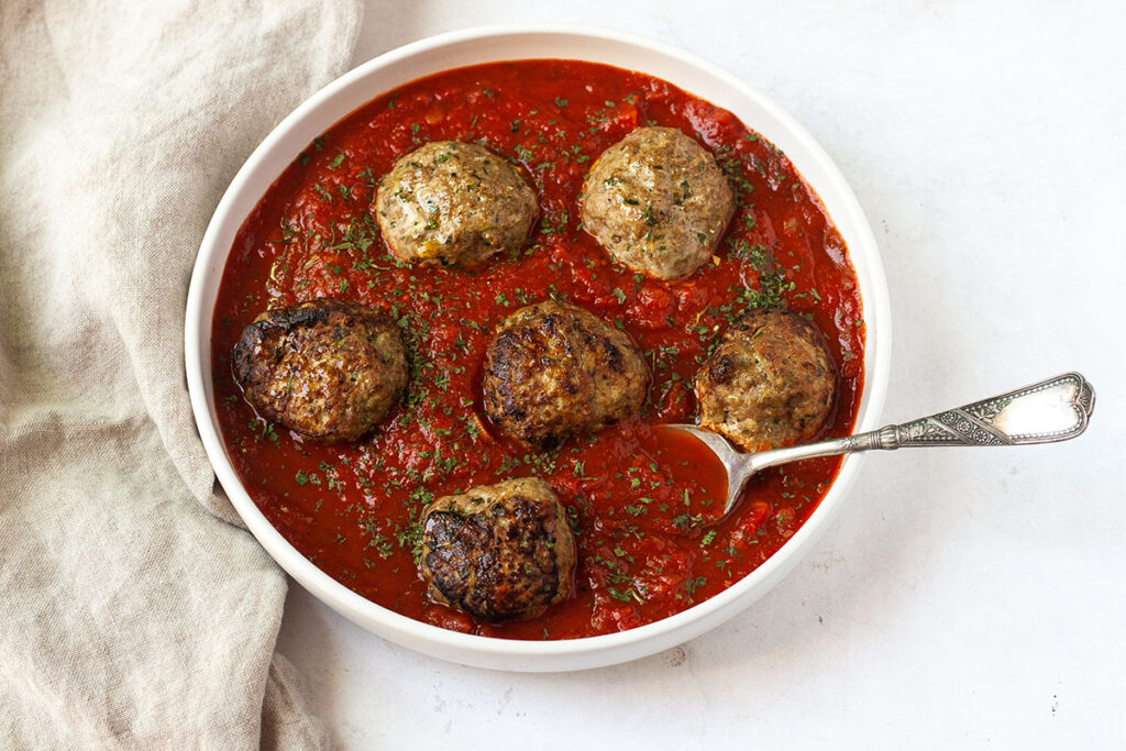 eggplant and turkey baked meatballs in bowl of sauce